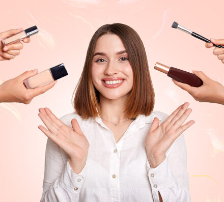 A woman displays various makeup products, showcasing her collection of cosmetics in a bright, well-lit setting.